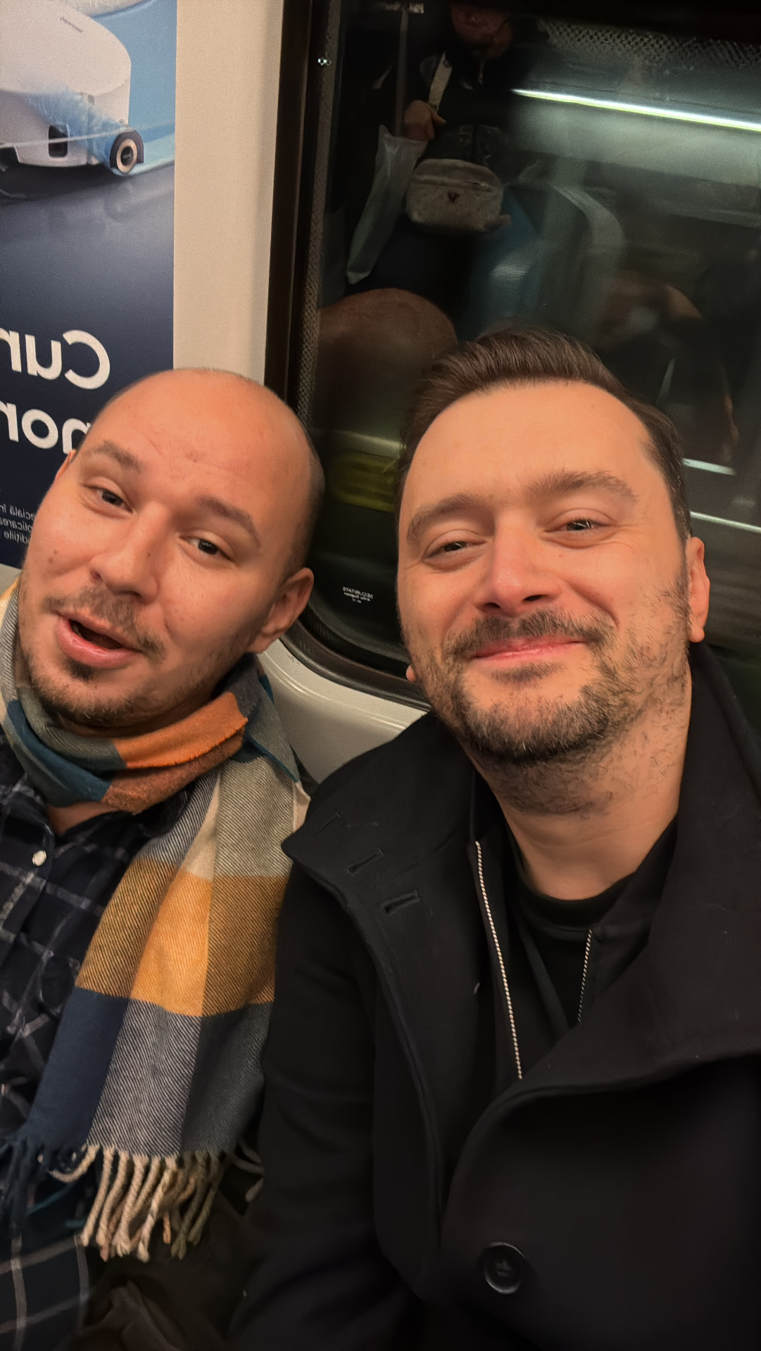 Adi and Bala smiling together on a train